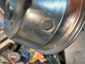Chamfer applied to 6" main wheel hub valve tube hole. This chamfer ensures the tube is not pinched by not chafed by a relatively sharp corner as supplied. A chamfer also applied to other side, to further reduce chance of chafing.