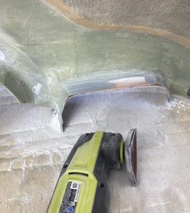 Using 40 grit paper to sand away the underlying fiberglass to make room for the rubber seals.